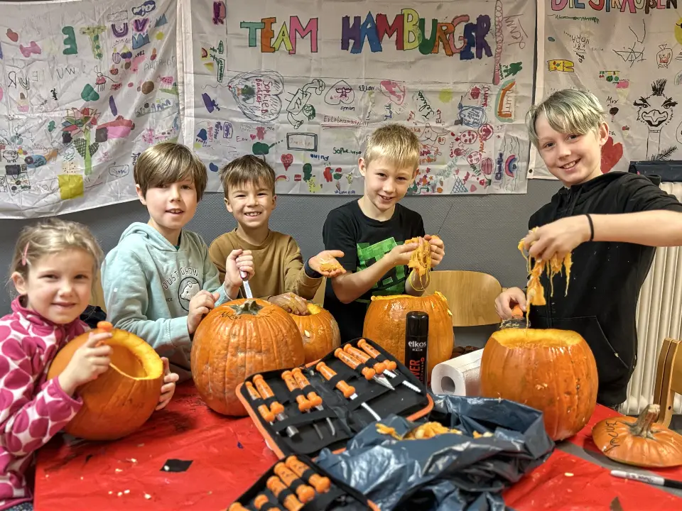 Kinder beim Kürbisschnitzen in der Ferienbetreuung in Essen während der Herbstferien.