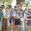 Teilnehmer einer Sommerfest-Fahrradrallye bei der Siegerehrung auf den Rheinwiesen in Düsseldorf mit Urkunden, Siegersekt und Teamfoto nach einem erfolgreichen Teambuilding-Event