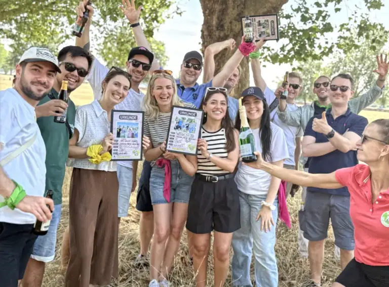Siegerehrung der Sommerfest Fahrradrallye auf den Rheinwiesen in Düsseldorf Teilnehmer einer Sommerfest-Fahrradrallye bei der Siegerehrung auf den Rheinwiesen in Düsseldorf mit Urkunden, Siegersekt und Teamfoto nach einem erfolgreichen Teambuilding-Event