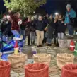 Winterliches Glühwein-Event mit Spielstation: Eine Gruppe feiert bei einer Glühweinwanderung und steht jubelnd hinter weihnachtlich dekorierten Spielkörben, während ein festlich beleuchteter Bollerwagen daneben steht.