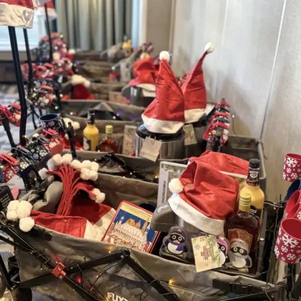 Festlich dekorierte Bollerwagen für eine winterliche Glühweinwanderung: mit Weihnachtsmützen, Glühweinbechern, Getränken und Lichterketten ausgestattete Wagen, bereit für eine Glühweinrallye oder ein winterliches Team-Event.