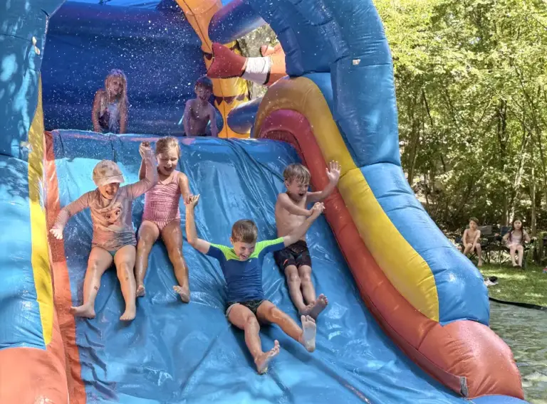 Huepfburg-mit-Wasser-Riesenrustche-Huepfburgen-Verleih Fröhliche Kinder auf einer riesigen, aufgeblasenen Hüpfburg, die mit Wasser bespielt wird.