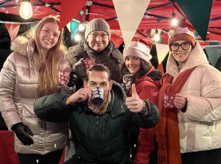 Weihnachtsfeier mit Glühwein: Glühweinwanderung als winterliches Team-Event Teilnehmer einer Glühweinwanderung stoßen bei einer winterlichen Weihnachtsfeier gemeinsam an und genießen Glühwein als Team-Event
