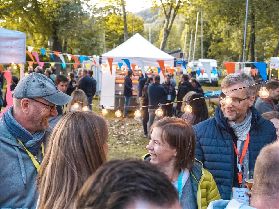 XXL-Jahrmarkt als Firmenevent mit Jahrmarktständen, Lichterketten und Gästen in geselliger Atmosphäre