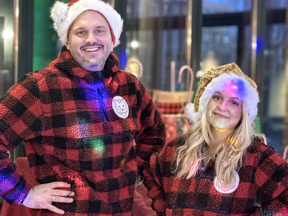 Winter-Olympiade Indoor mit dem Erlebnismacher Team in Winterjacken und Weihnachtsmützen auf einem Firmenevent zur Weihnachtszeit.