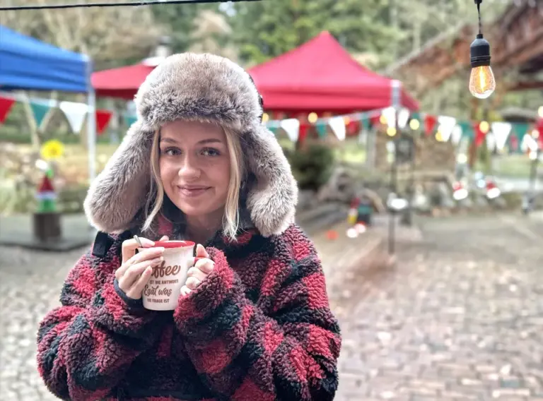 Firmenweihnachtsfeier mit Glühwein auf einem mobilen Weihnachtsmarkt Person mit Glühwein auf einer Firmenweihnachtsfeier als mobiler Weihnachtsmarkt mit festlicher Beleuchtung