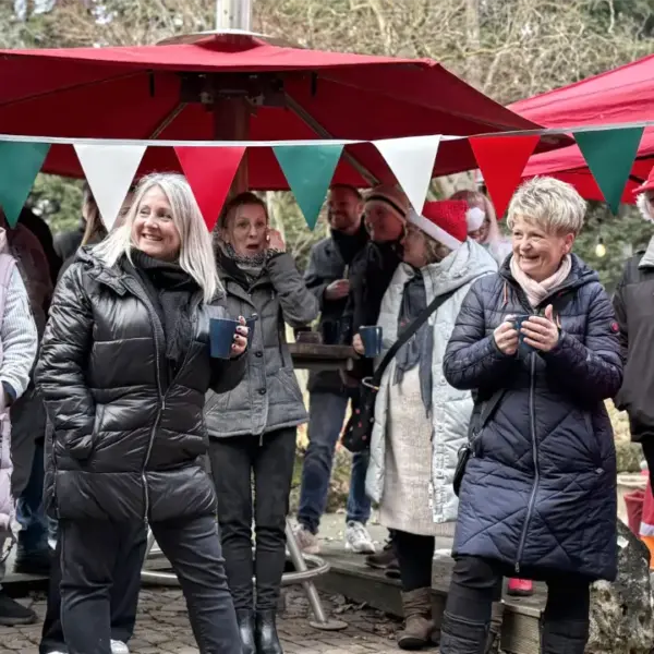 Mitarbeitende auf einer Firmenweihnachtsfeier als mobiler Weihnachtsmarkt mit Glühwein, Marktständen und winterlicher Atmosphäre