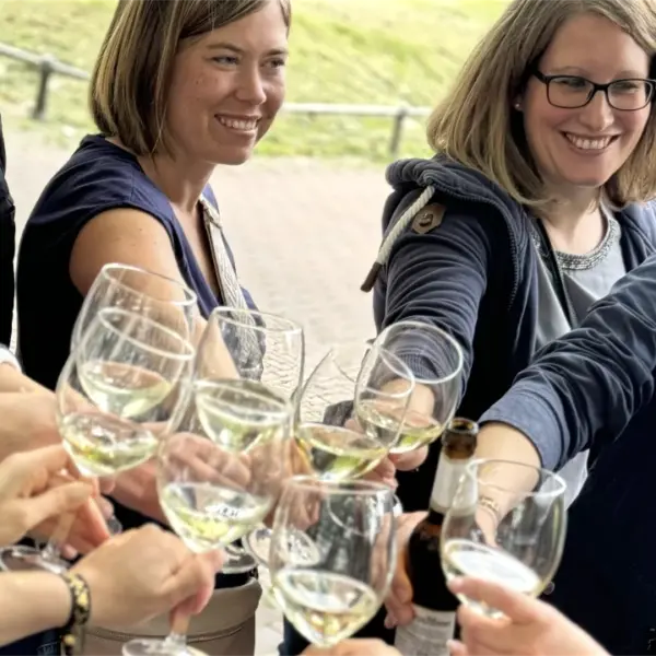 Sommerfest Firma Weinrallye Team stößt mit Weingläsern an beim Outdoor Firmenevent