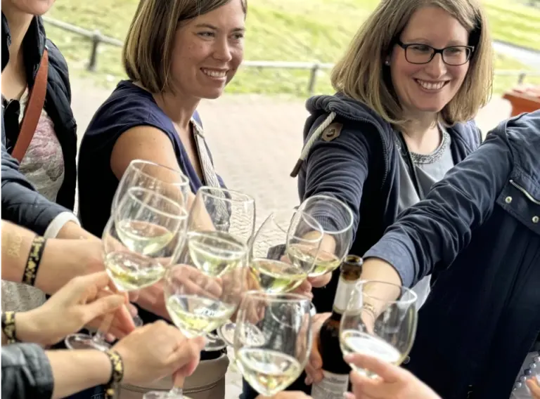 Sommerfest Firma Weinrallye – Team stößt gemeinsam mit Wein an Sommerfest Firma Weinrallye Team stößt mit Weingläsern an beim Outdoor Firmenevent