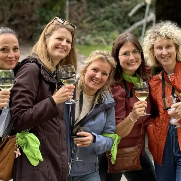 Sommerfest Firma Weinrallye Team stößt mit Wein an und lacht beim Outdoor Firmenevent