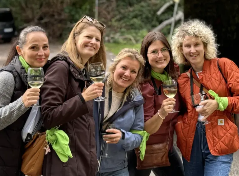 Sommerfest Firma Weinrallye Team stößt mit Wein an und lacht beim Outdoor Firmenevent