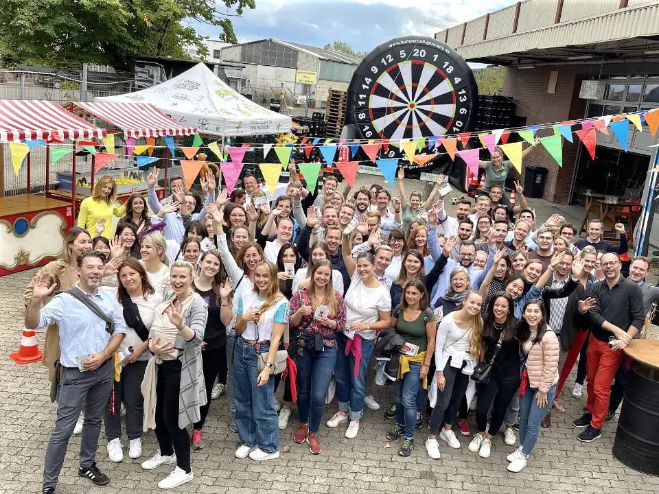 Sommerfest Ideen für Firmen – großes Team bei einem Jahrmarkt-Sommerfest mit Teamspielen