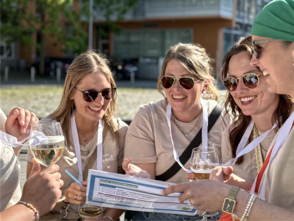 Sommerfest Firma Weinrallye Team sitzt zusammen löst Aufgaben und trinkt Wein beim Firmenevent