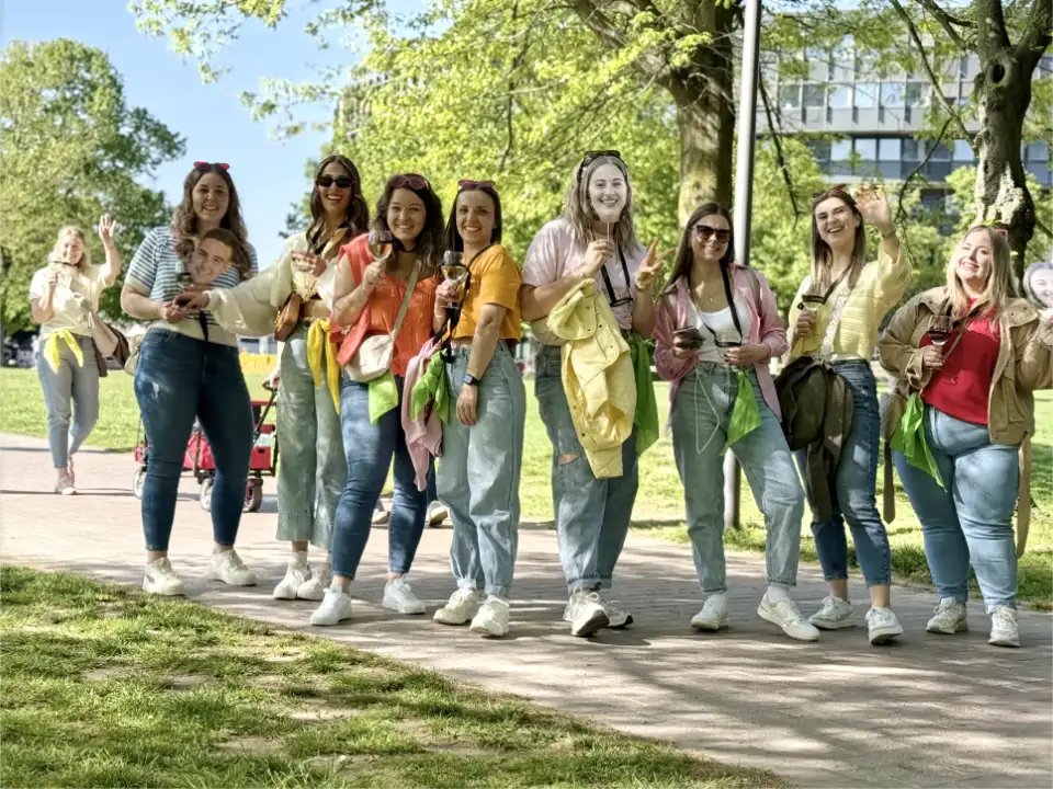 Eine Gruppe von Frauen feiert einen Junggesellinnenabschied bei einer Weinwanderung und Weinrallye in Düsseldorf. Die Teilnehmerinnen laufen gemeinsam durch einen Park, trinken Wein und genießen einen entspannten JGA in Düsseldorf.