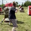 Mehrere Mitarbeitende spielen Arrow Games bei einem Outdoor-Event für Unternehmen und treten mit Pfeil und Bogen hinter aufblasbaren Hindernissen gegeneinander an