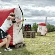 Mitarbeiter zielt beim Arrow Tag während eines Betriebsausflugs für Unternehmen mit Pfeil und Bogen hinter einem aufblasbaren Hindernis