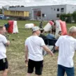 Mitarbeitende verfolgen ein mobiles Arrow-Tag-Spiel während einer Firmenfeier mit spannenden Teamduellen auf einem Outdoor-Spielfeld
