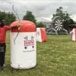 Teilnehmer spielt mobiles Arrow Tag auf einem professionell aufgebauten Outdoor-Spielfeld mit aufblasbaren Hindernissen bei einem Firmenevent