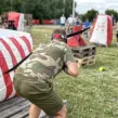 Mitarbeiter sucht beim Outdoor-Teamevent mit Arrow Tag Deckung hinter einem aufblasbaren Hindernis und entwickelt gemeinsam mit seinem Team eine Spielstrategie