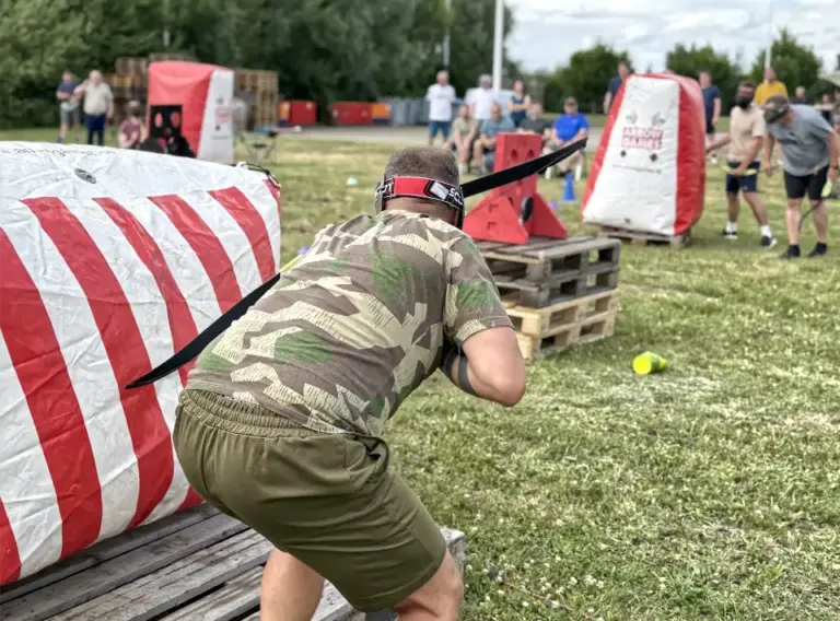 Outdoor-Teamevent mit Arrow Tag für Unternehmen Mitarbeiter sucht beim Outdoor-Teamevent mit Arrow Tag Deckung hinter einem aufblasbaren Hindernis und entwickelt gemeinsam mit seinem Team eine Spielstrategie