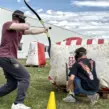 Zwei Mitarbeitende spielen mobiles Arrow Tag bei einem Team Event für Unternehmen und nutzen gemeinsam ein aufblasbares Hindernis als Deckung